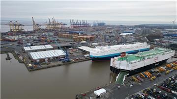Auf dem Bild ist das Autoterminal in Bremerhaven zu sehen, im Hintergrund stehen Kräne des Containerterminals.