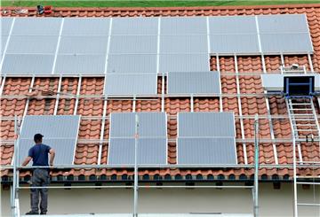 Ein Arbeiter montiert Solarmodule auf einem Dach