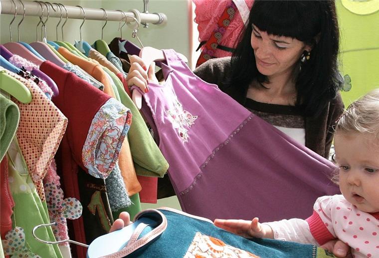 Stadthalle Bremerhaven lädt zum „Kids & Co“-Flohmarkt ein Eine Frau und ein Baby betrachten Babykleidung.
