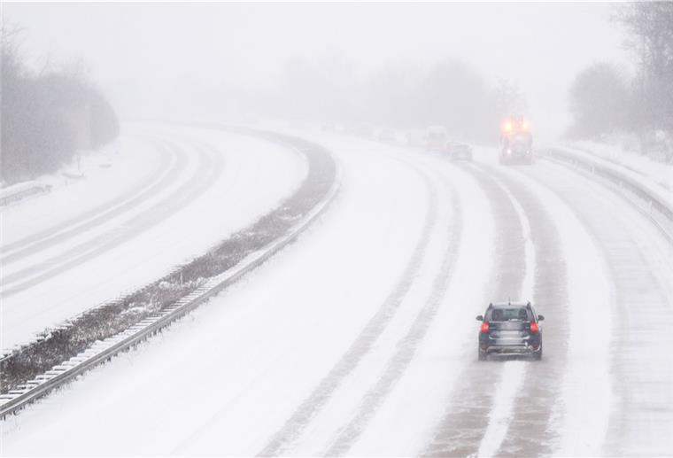 Ein Auto fährt bei Schneefall über die Autobahn A7.
