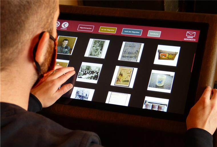Auswandererhaus startet neues Medienkonzept Auf der einen Seite des Biografien-Portals befindet sich ein gläserner Schaukasten, auf der anderen ein Touchscreen-Monitor mit einer dahinterliegenden Datenbank.