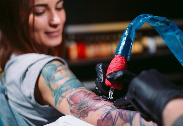 Eine Frau lässt sich tätowieren und lächelt dabei. In Bremerhaven findet am 15. und 16. März eine Tattoo-Messe statt, die sich an Frauen richtet. 