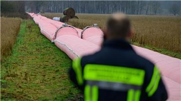 Auf einem Feld liegt ein Teil von einem mobilen Deich, welcher mit Wasser befüllt ist.