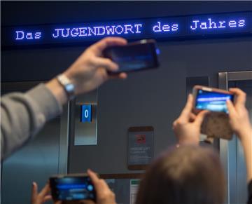 Auf einem Laufband erscheint "Jugendwort des Jahres" über den digitalen Newsticker eines Hotels.