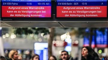 Auf einer Anzeigetafel steht der Schriftzug „Aufgrund eines Warnstreiks kann es zu Verzögerungen bei der Abfertigung kommen“.