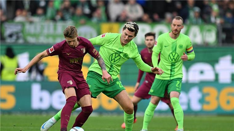 Amoura bewahrt Wolfsburg vor Niederlage gegen Augsburg Augsburgs Kristijan Jakic (l) spielt gegen Wolfsburgs Jonas Wind.