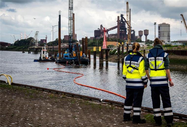 Die Spitze eines gesunkenen Schleppers ragt aus dem Wasser hinter einer Ölsperre. Ein umstürzender Kran hat ein Schiff nahe der Schleuse Oslebshausen versenkt