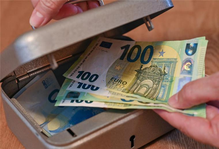  Eine Frau holt Eurobanknoten aus einer kleinen Geldkassette 