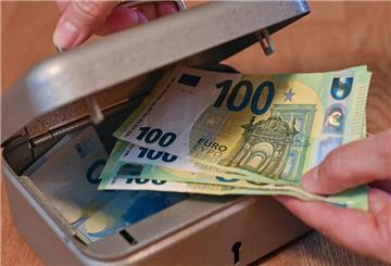  Eine Frau holt Eurobanknoten aus einer kleinen Geldkassette 