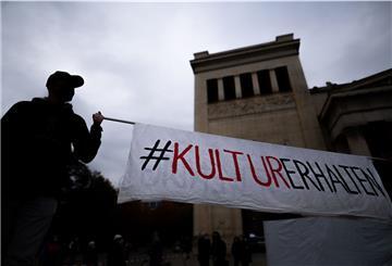 Zwei Männer auf Stelzen halten auf dem Königsplatz ein Banner mit der Aufschrift «#KulturErhalten». 