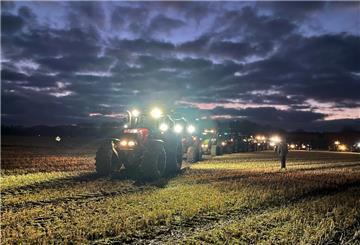 Beleuchtete Traktoren fahren zur Abendzeit auf eine Weide