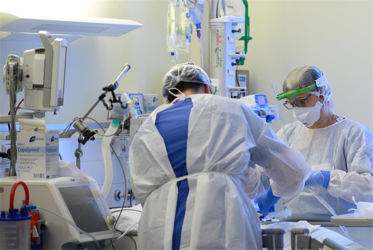 Intensivpflegerinnen sind in Schutzkleidungen auf der Intensivstation einer Klinik mit der Versorgung von Corona-Patienten beschäftigt.