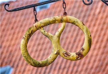 Eine Brezel hängt wie ein Aushängeschild vor einer Bäckerei.