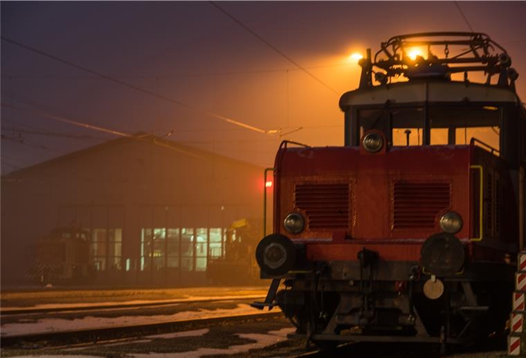 Frau verpasst Bahn und fährt auf Güterzug mit Bahnhof mit Güterzug bei nächtlicher Beleuchtung schafft unheimliche Stimmung