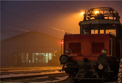 Bahnhof mit Güterzug bei nächtlicher Beleuchtung schafft unheimliche Stimmung