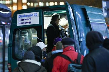 Bedürftige stehen in der Innenstadt von Hamburg bei der Ausgabe von Essen und heißen Getränken am Mitternachtsbus der Diakonie Hamburg. Seit 20 Jahren hilft der Diakonie-Mitternachtsbus obdachlosen Menschen auf Hamburgs Straßen mit Essen, heißen Getränken sowie Decken und Schlafsäcken. 