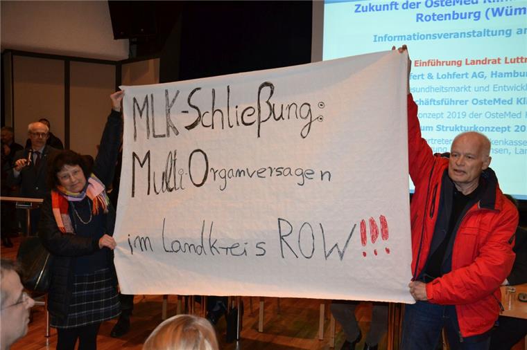 Das MLK muss sterben, damit die Bremervörder Klinik leben kann Begleitet von tosendem Applaus trug Dr. Wolfgang Trescher gemeinsam mit seiner Frau Ilonka Timm-Trescher, einer ehemaligen Krankenschwester des MLK, ein Transparent in den überfüllten Rathaussaal. Landrat Hermann Luttmann (hinten links) ließ sich davon nicht beeindrucken. Er fuhr mit seiner Einführung fort.