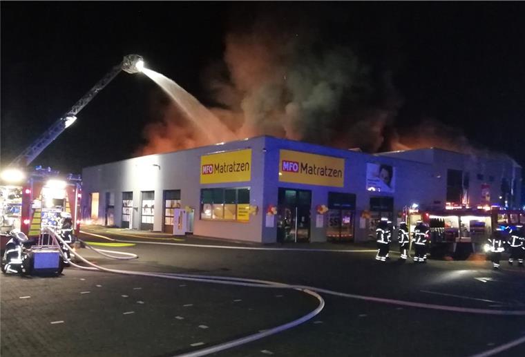 Lingen: Baumarkt geht in Flammen auf Qualm und Rauch über einem Gebäude in der Nacht. Feuerwehr mit Drehleiter löscht. Feuerwehrleute.