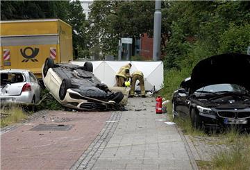 Ein stark beschädigter Taxi-Wagen liegt auf dem Dach nahe einer Straße. Weitere Fahrzeuge stehen mit deutlichen Schäden in der Nähe.