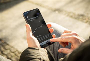 Ein Mann hält ein Handy in der Hand, wo die App Trade Republic geöffnet ist.