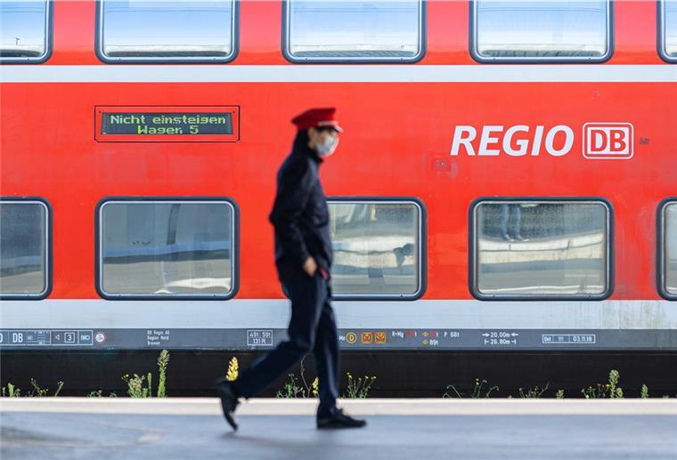 Bremerhaven: Es drohen wieder Zugausfälle Ein Mitarbeiter der Deutschen Bahn (DB) läuft auf einem Bahnsteig und ein Zug der DB Regio steht auf einem Gleis dahinter.