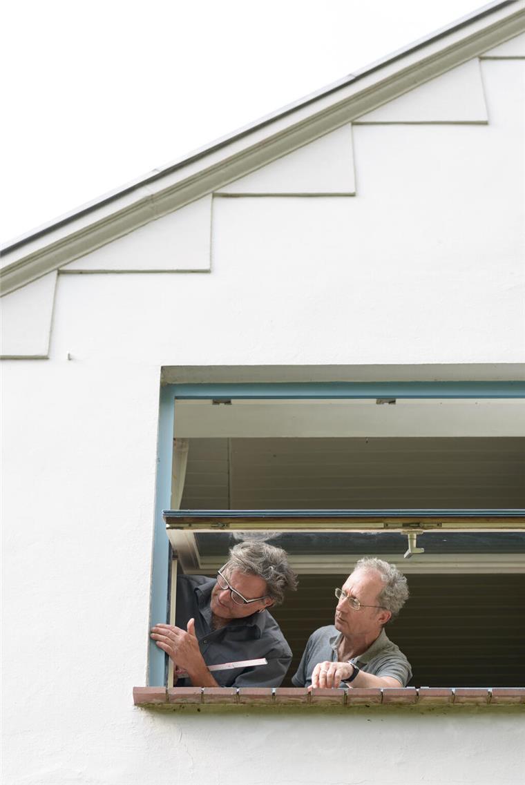Gefragter denn je: die Dämmvisite Zwei Männer gucken aus einem Fenster und schauen sich die Fensterdichtung genau an