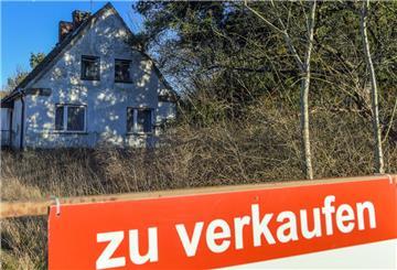 Ein Schild mit der Aufschrift «zu verkaufen» steht auf einem Grundstück mit einem Einfamilienhaus. 