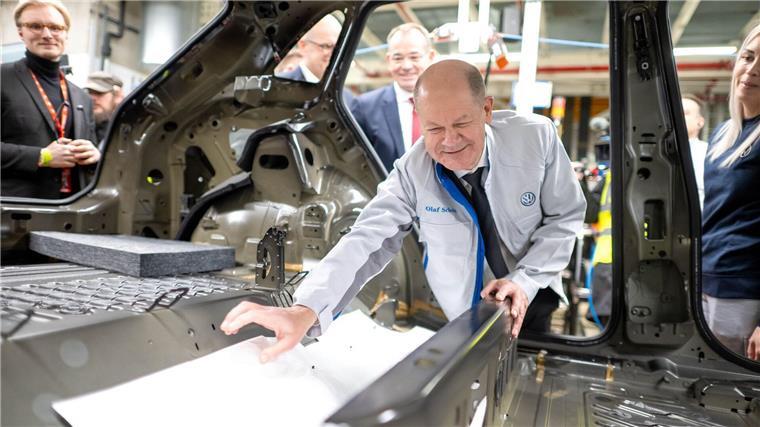 „Elektromobilität funktioniert“ - Kanzler besucht VW Emden Bei seinem Besuch im Emder VW Werk hilft Bundeskanzler Olaf Scholz (SPD) beim Einbau einer Dämmmatte.