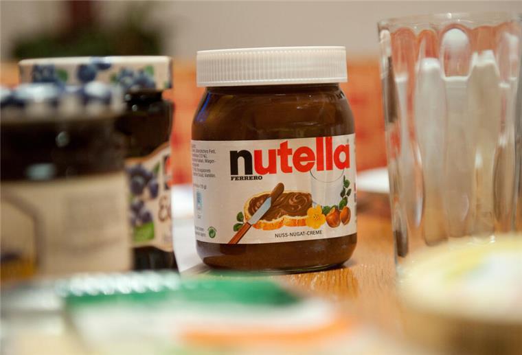 Ein Glas Nutella steht auf einem Frühstückstisch.