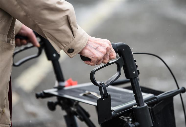 Eine ältere Person geht mit einem Rollator.
