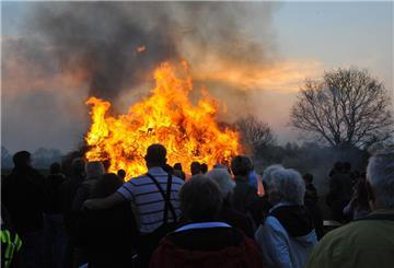 Menschen blicken auf ein brennendes Osterfeuer.