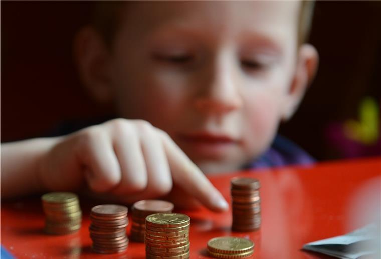 Schiffdorf: Im Haushalt droht ein dickes Minus Ein Junge sitzt an einem roten Tisch und zählt Geld.