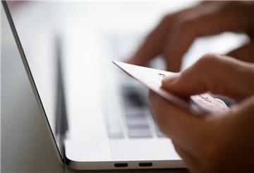 Eine Frau tippt Kreditkartendaten in ihren Laptop ein. Auf Kleinanzeigenportalen tummeln sich Betrüger mit ganz unterschiedlichen Betrugstaktiken.
