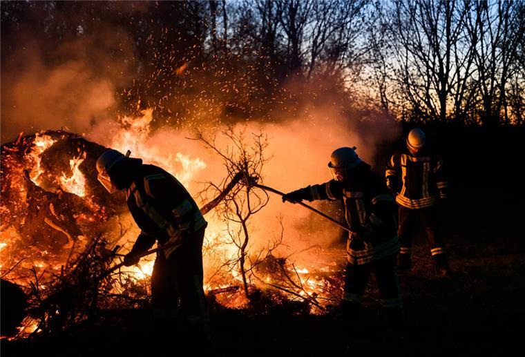 Todesfalle für Wildtiere: Osterfeuer vor dem Abbrennen umschichten Feuerwehrkräfte schichten ein Osterfeuer auf.
