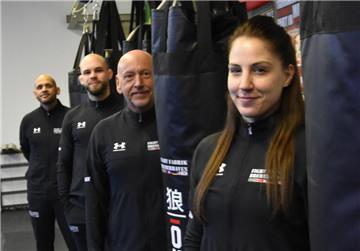 Eine Frau und drei Männer stehen inmitten von Boxsäcken, die von der Decke hängen.