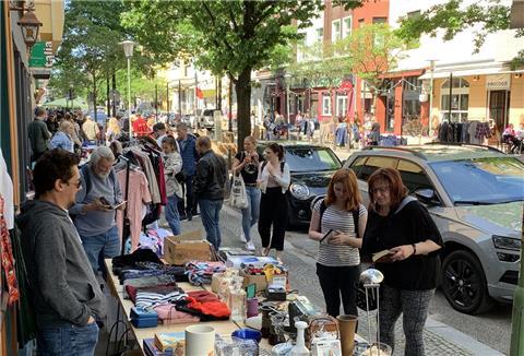 Besucherinnen und Besucher stöbern an mehreren Flohmarktständen in der Straße "Alte Bürger"