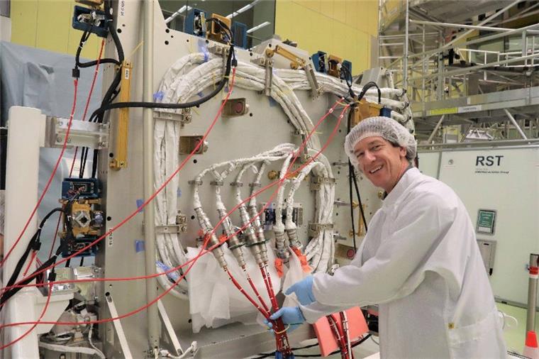 Preiswerte Experimente im Orbit dank Bremer ISS-Plattform Startklar: Ein Bündel weißer Kabel zeigt Programmleiter Andreas Schütte, vor der Plattform „Bartolomeo“. Die Kabel werden über das tonnenförmige ISS-Modul „Columbus“ gelegt und sorgen für Strom und Datenfluss.