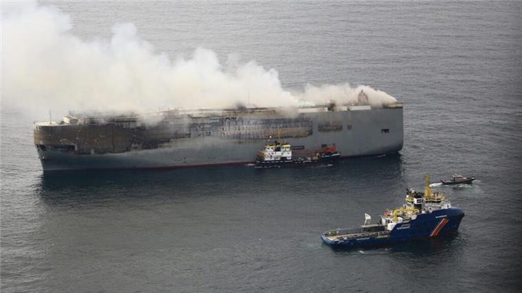 Autotransporter in Flammen, Rettungsboot der Küstenwache in der Nähe. 