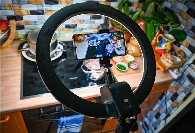 Eine Ringleuchte und ein Smartphone auf einem Stativ sind oberhalb der Arbeitsplatten aufgebaut.