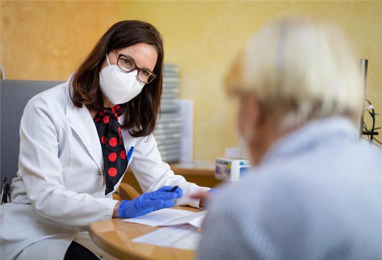 Notbremse: Kommt die Vier-Tage-Woche für Arztpraxen? Eine Ärztin mit Schutzmaske spricht mit einer Patientin.