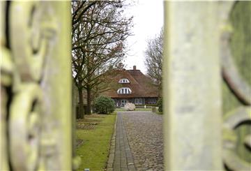 Blick durch ein Gartentor auf Bauernhaus.