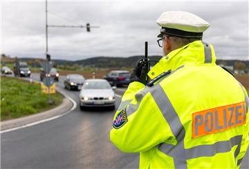 Polizist kontrolliert das Tempo von vorbeifahrenden Fahrzeugen auf einer Straße. An der bundesweiten Blitermarathon nehmen zwölf Bundesländer teil - darunter auch Bremen und Hamburg.