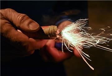 Ein Mann zündet einen Silvesterknaller an.