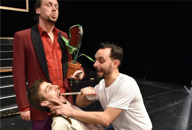 Audrey II wuchert wie das Virus Mann steckt Feile in den Mund eines anderen Mannes