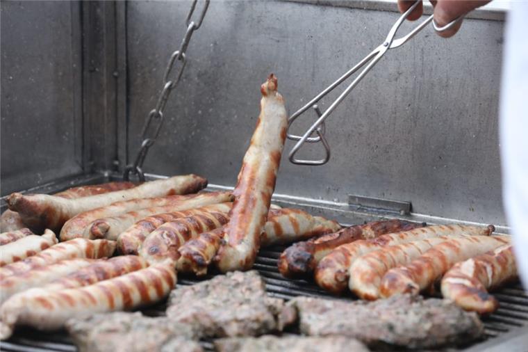 Grillwetter angesagt: Was ist erlaubt und was nicht? Bratwürste und anderes Fleisch liegen auf einem Holzkohlegrill.