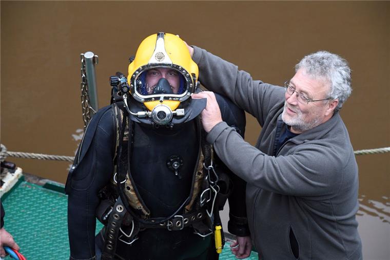 Einsatz im schlickigen Hafenwasser: Taucher ersetzen Schienen der Fischereihafenschleuse Bremenports-Taucher sanieren die Doppelschleuse:
Tauchermeister Michael Lammert hilft seinem "Azubi" Morten Fischer beim Ablegen der Ausrüstung.
Foto Scheer