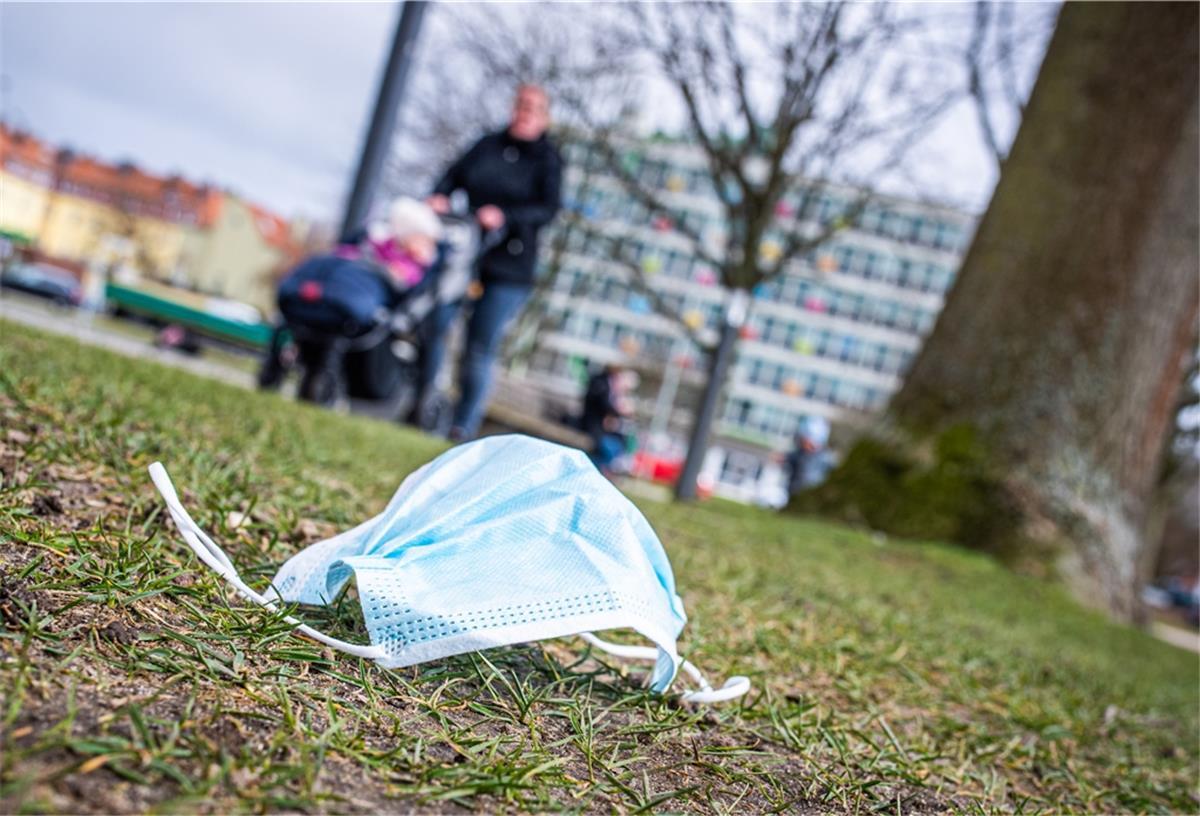 Eine getragene OP-Maske liegt auf dem Rasen.