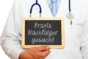 Ein Mann im Arztkittel hält ein Schild in der Hand.