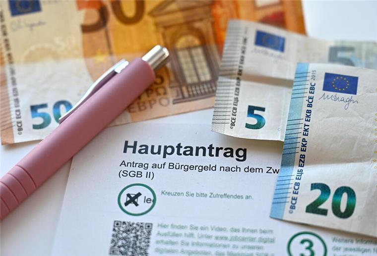 Alle Bürgergeld-Empfänger betroffen! Diese knallharten Pläne sorgen für Bestürzung Der Hauptantrag für Bürgergeld liegt neben Geldscheinen auf einem Tisch.