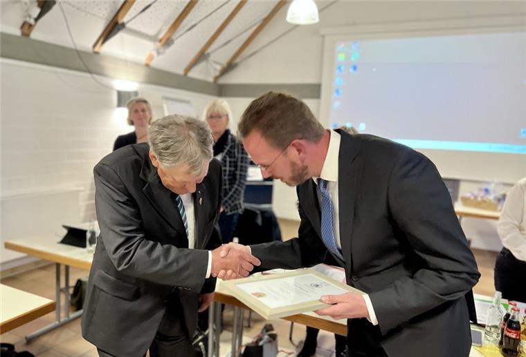 Wurster Nordseeküste: Ehrenbürgerschaft für Jochen Wrede Zwei Männer in grauen Anzügen schütteln sich die Hände und verbeugen sich voreinander.